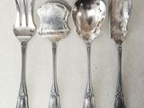 four spoons and a fork are lined up on a table