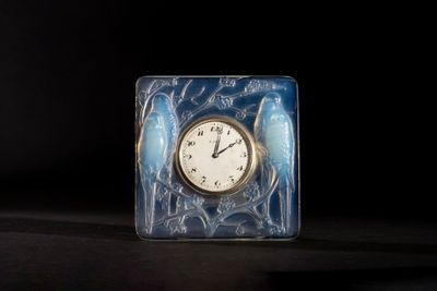 a clock that is sitting on a table in front of a black background