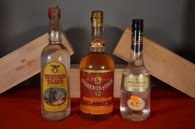 three bottles of liquor sitting on a table next to a wooden box