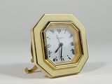 a small gold clock with roman numerals on it
