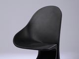 une chaise noire posée sur une surface blanche