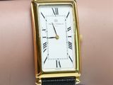 a gold and black wrist watch on a woman ' s arm