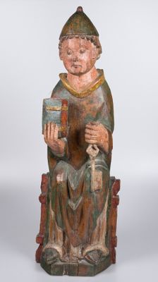 une vieille statue en bois représentant un homme assis sur une chaise, tenant un livre