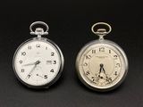deux montres de poche en argent posées l'une à côté de l'autre sur une surface noire