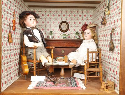 deux poupées assises dans une maison de poupées