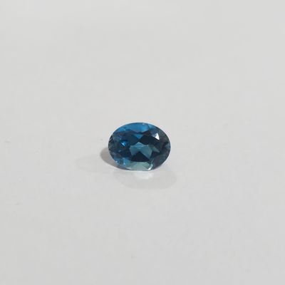 an oval blue topaze gems on a white surface