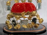 a gold and black clock with a red velvet cushion on top of it