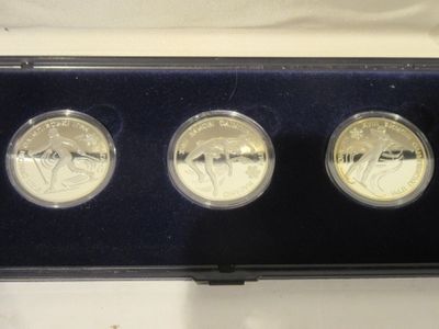 trois pièces d'or dans un écrin noir posé sur un fond blanc