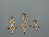 three gold pendants of different shapes and sizes on a gray surface