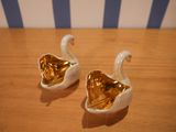 two white and gold swans sitting on a wooden table