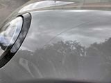 a close up of a car ' s headlight with a reflection of trees in the background