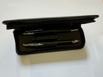 un étui noir contenant trois stylos, posé sur une table
