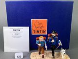two figurines of two people and a dog are on a table