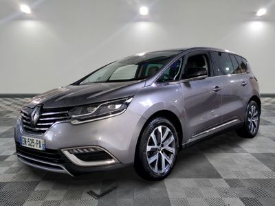Une voiture grise est garée dans une grande pièce dont le sol est en damier.