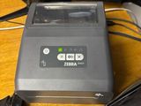 a zebra printer sitting on a desk next to a computer monitor