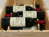 bottles of red wine in a wooden box on a white surface