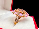 a gold ring with pink stones in a red box