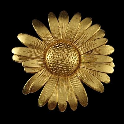 broche en métal plaqué or en forme de fleur sur fond noir