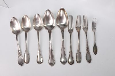 six spoons and six forks are lined up on a white surface