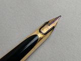 the tip of a fountain pen with a black nib resting on a white surface