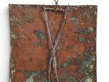 an image of a piece of rusted metal hanging on a white wall