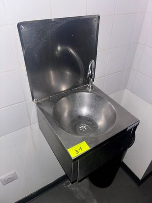 un évier en acier inoxydable dans le coin d'une toilette publique