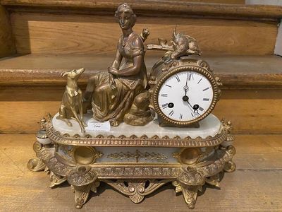 a clock sitting on top of a table with a statue on top of it