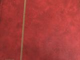 a red book with gold trim sitting on a table