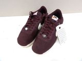 une paire de baskets bordeaux avec des lacets blancs sur un fond blanc