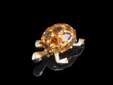 une photo d'une bague sertie d'un diamant jaune posée sur une surface noire