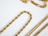 many chains of gold on a white surface