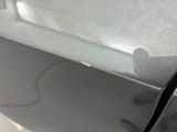 the rear end of a car with a dent in it ' s bumper