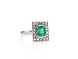 a close up of a ring with a green stone surrounded by white diamonds