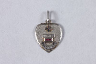 a close up of a silver heart shaped charm on a white surface