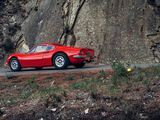 a red sports car driving down the road next to a large rock