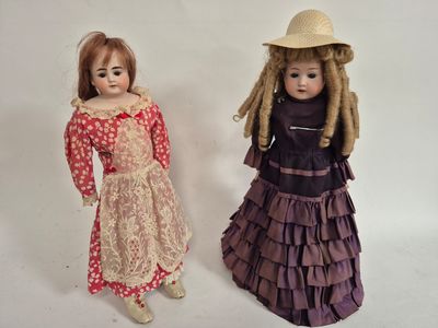 two dolls standing next to each other on a white surface