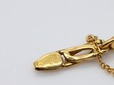 an image of a gold shoe charm with a chain on a white surface