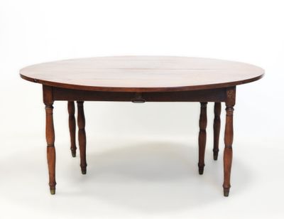 La table est en bois et possède un plateau rond.