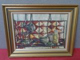 tableau représentant une scène de cuisine, dans un cadre doré, posé sur une nappe rouge
