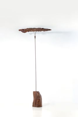 une sculpture représentant une feuille, posée sur un socle, sur une surface blanche