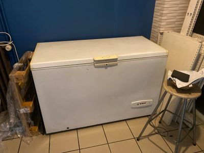 un petit congélateur coffre blanc dans un coin de la pièce