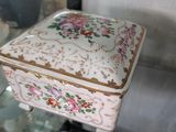 une assiette blanche bordée d'or et une boîte blanche ornée d'un motif floral