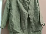 green jacket hanging on a hanger on a wall in a room