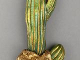 figurine de cactus dorée et verte posée sur un morceau de bois