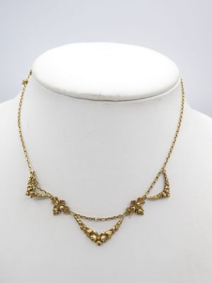 a gold necklace on a mannequin neck with a flower design