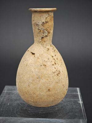 un vieux vase en pierre posé sur un socle en verre