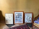 three framed pictures on the floor next to a chair and a rug