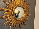 a gold sunburst hanging on the wall above a toilet