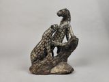 une statue représentant un chien et un chat assis sur un rocher