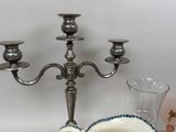 a silver candelab with three candles and a bowl on the table